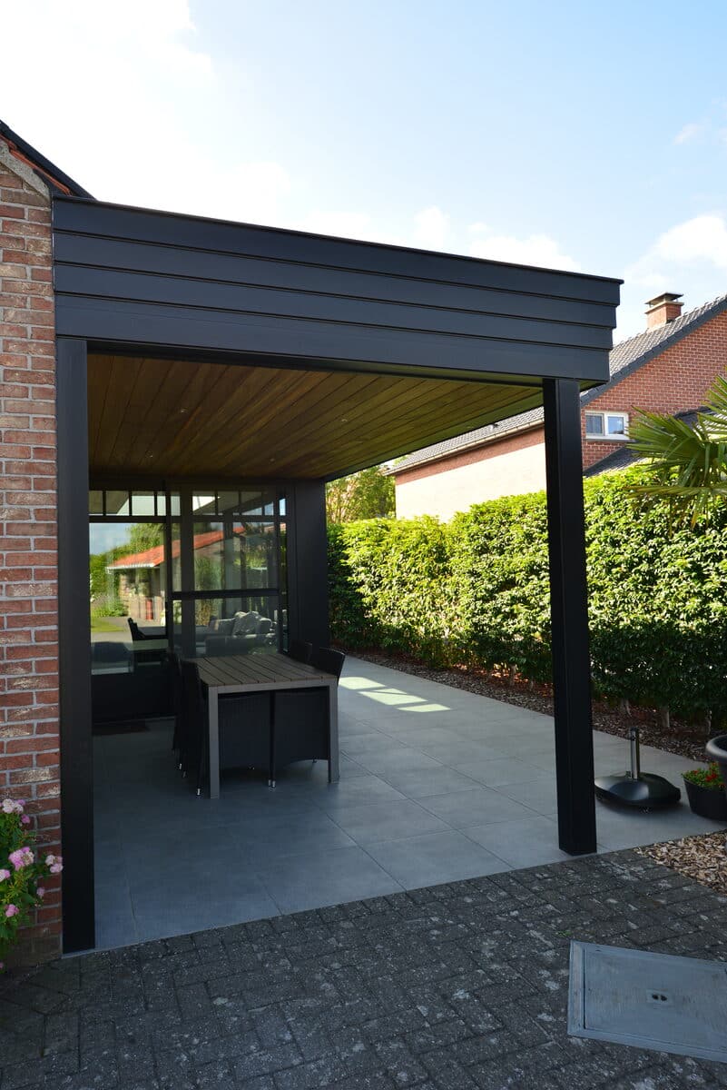 Zwarte aluminium terrasoverkapping met houten plafond aan een bakstenen woning