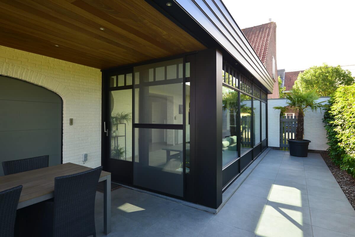 Zwarte steellook veranda met glazen wanden aan een terras