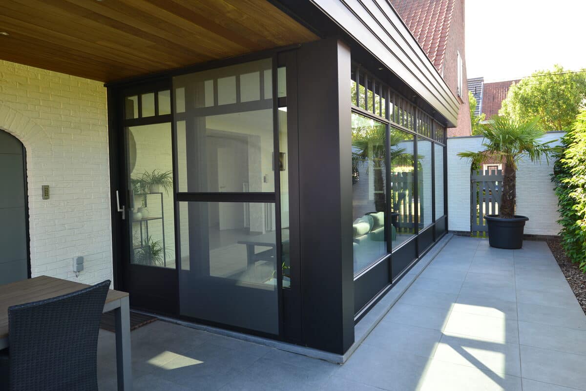 Zwarte aluminium veranda met glazen wanden aan een terras