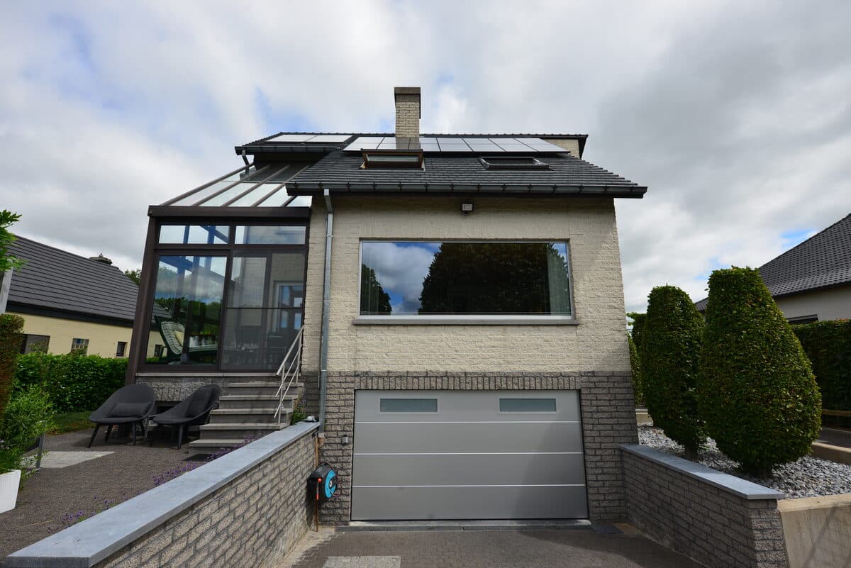 Woning met glazen veranda en lichtgrijze sectionale garagepoort