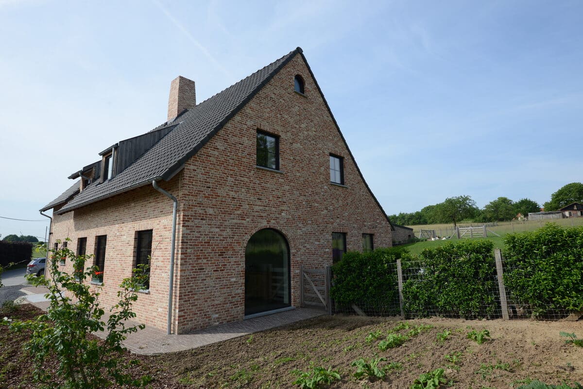 Bakstenen woning met zwarte steellook ramen en een glazen boogopening