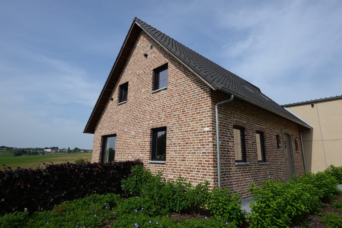 Bakstenen woning met zwarte aluminium ramen en zicht op de velden