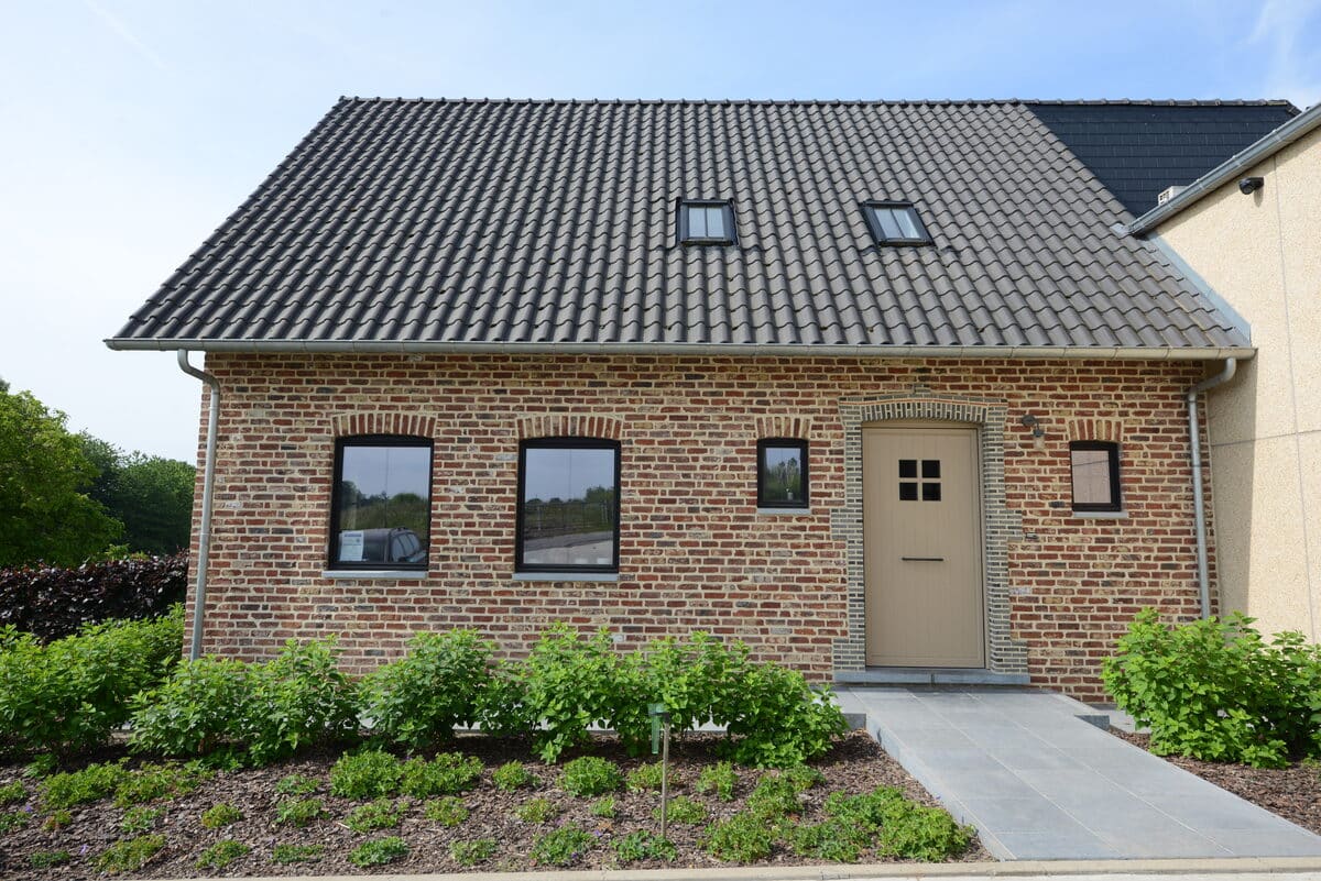 Bakstenen woning met zwarte aluminium ramen en een beige buitendeur